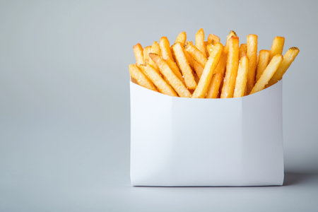 Delicious golden french fries in a white paper containerの素材