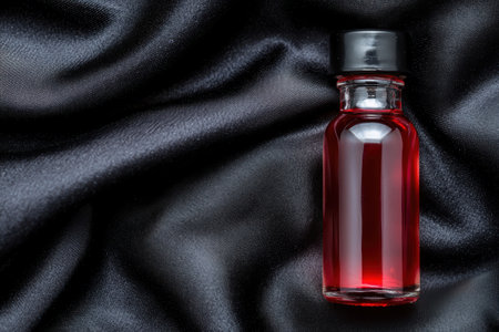 Elegant red perfume bottle on black satin fabricの素材