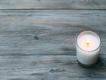 Lit candle on wooden tableの素材