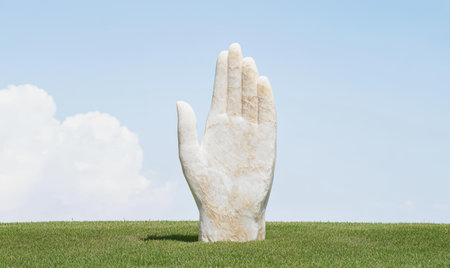 large hand sculpture in grassy fieldの素材