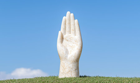 Outstretched hand statue in grassy fieldの素材