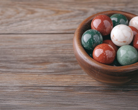 Colorful stone spheres in a wooden bowl on a rustic wooden surfaceの素材