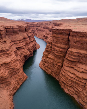Aerial view of a stunning red rock canyon with a deep blue river flowing through itの素材