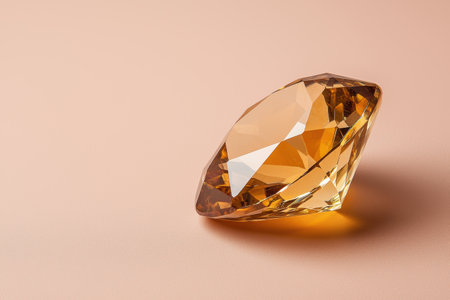 Close-up of a sparkling golden diamond on a peach backgroundの素材