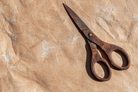 Rusty scissors on crumpled brown paper backgroundの素材