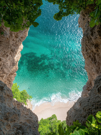 Secluded cove with turquoise water and white sand beach seen from a rocky overlookの素材