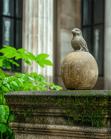 Stone bird statue on a mossy wallの素材