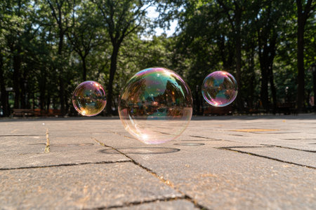 Large soap bubble floats over pavement in parkの素材
