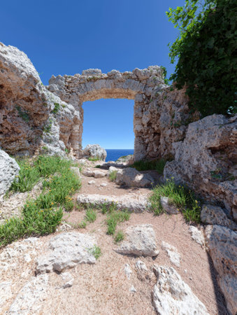 Stone archway overlooking the ocean on a sunny day.の素材