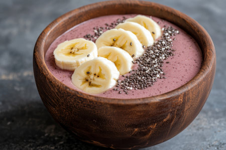 A wooden bowl filled with a smoothie, banana slices, and chia seeds.の素材