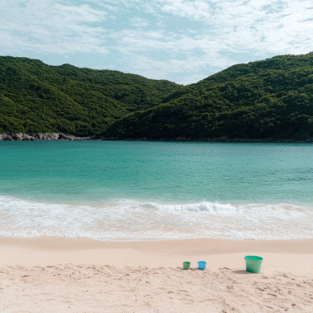 Turquoise water meets a sandy beach with green hills in the background.の素材