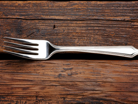 Silver fork on a rustic wooden table.の素材