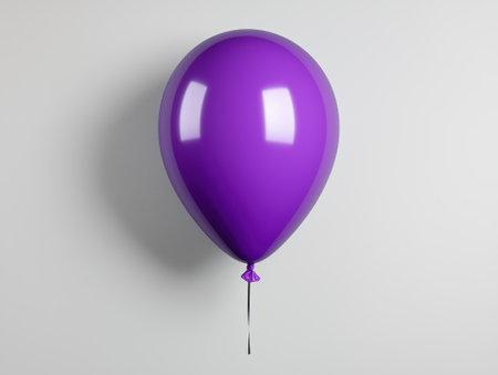 A shiny purple balloon floats against a white wall.の素材