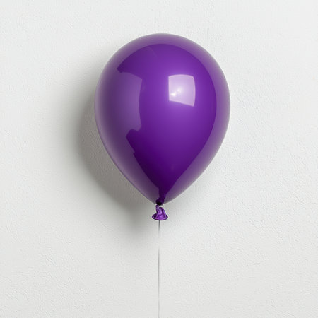 A shiny purple balloon floating against a white wall.の素材