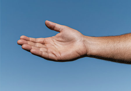 Open hand against a blue sky background.の素材