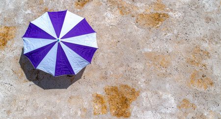 Purple and white beach umbrella on travertine stone.の素材