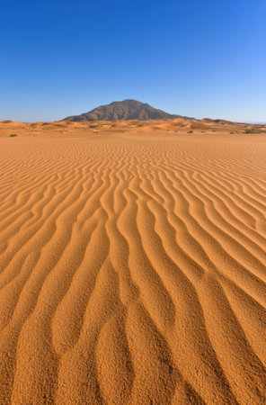 Sand dunes in the desert with a mountain in the background.の素材