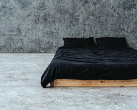 Minimalist bedroom interior with black bedding and concrete wall.の素材
