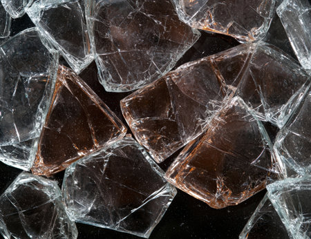 Scattered shards of broken glass on a dark surface.の素材