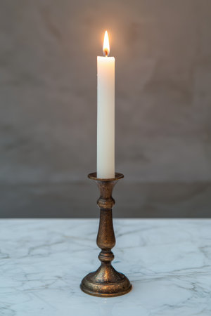 Illuminated candle flame in vintage bronze candlestick holder.の素材
