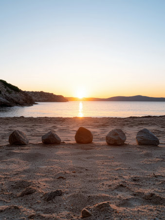 Zen stones aligned on sandy beach at sunset.の素材