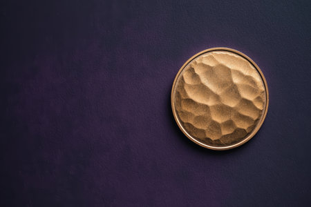 Hammered bronze coin on dark purple textured background.の素材