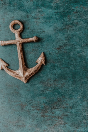 Vintage anchor on textured teal background, nautical theme.の素材