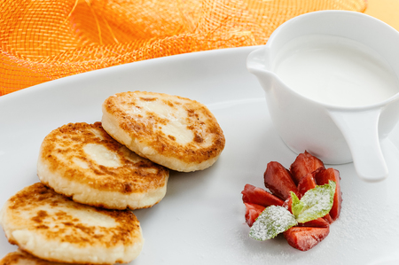 Hot pancakes on white plate with fresh strawberries and sour creamの写真素材