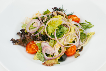 Mixed fresh salad with cherry-tomatoes, onion and olives isolated on white backgroundの写真素材