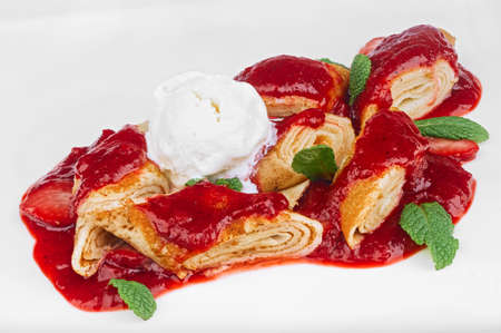 Homemade dessert of pancakes cut in pieces with scoop of vanilla ice cream and mint leaves isolated on whiteの写真素材