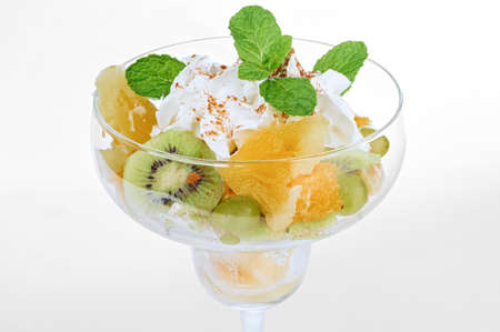 Vegetarian fruit mix with juicy slices of kiwi, pineapple, green grapes and whipped cream decorated with cacao powderの写真素材