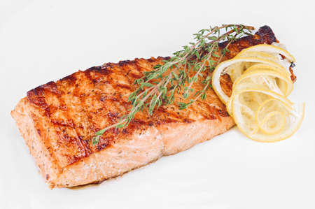 Fried red fish fillet cooked with spices isolated on white background close-upの写真素材