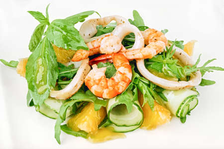 Organic seafood green salad with shrimps, squid rings, cucumber and arugula decorated with basil leavesの写真素材