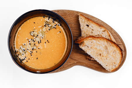 Traditional autumn vegetable soup with pumpkin and sesame seeds and two slices of toasted bread on...