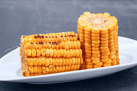 Freshly cooked organic ear of corn with kernels on white plate close-upの写真素材