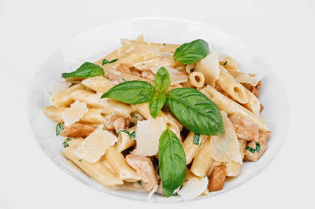 Cooked portion of pasta from Italian cuisine with fried chicken pieces, slices of parmesan cheese, decorated with basil isolated on white plateの写真素材