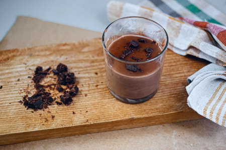 Glass of delicious energetic warm cacao beverage with dark chocolate on wooden board with napkinの写真素材