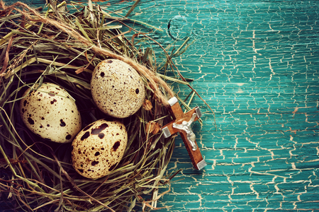 Easter rural background with quail eggs and wooden cross on ropeの写真素材