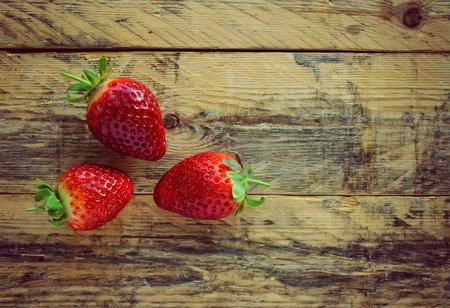 Three strawberries on old wooden table, rustic styleの写真素材