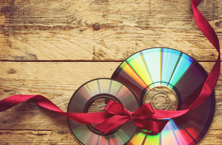 two cd disks and ribbon with bow on a wooden tableの写真素材