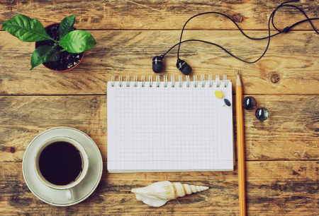 coffee cup, headphones, flower in pot, seashell, pen and notebook on wooden table, top viewの写真素材