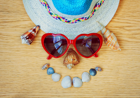 funny face of hat, glasses and seashells on wooden table, vacation conceptの写真素材