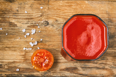 glass of tomato juice, cherry tomatoes, salt on an old wooden table, closeupの写真素材