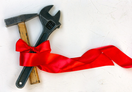 International Worker Solidarity Day, 1 May concept, hammer and wrench with red tape on a white textured surfaceの写真素材