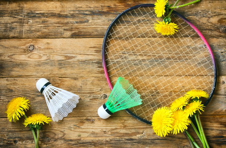Racket badminton and two shuttlecock on a wooden table, dandelions, summer sport, vacation conceptの写真素材