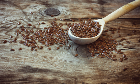 Flax seeds in wooden spoon, on an old table, selective focus, close-upの写真素材