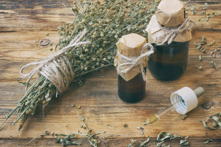 bunch of herb wormwood, jars of oil, on an old wooden table, rustic style, vintage pharmacyの写真素材