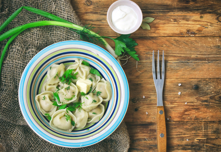 Dumplings with herbs, sour cream, napkin burlap on wooden table, traditional russian cuisineの写真素材