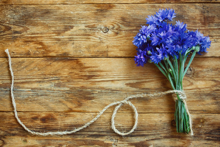 summer bouquet cornflowers tied rope on wooden table, greeting card, rustic styleの写真素材