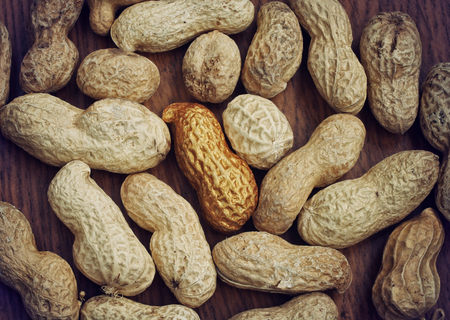 background with peanuts, single gold nut on old wooden table